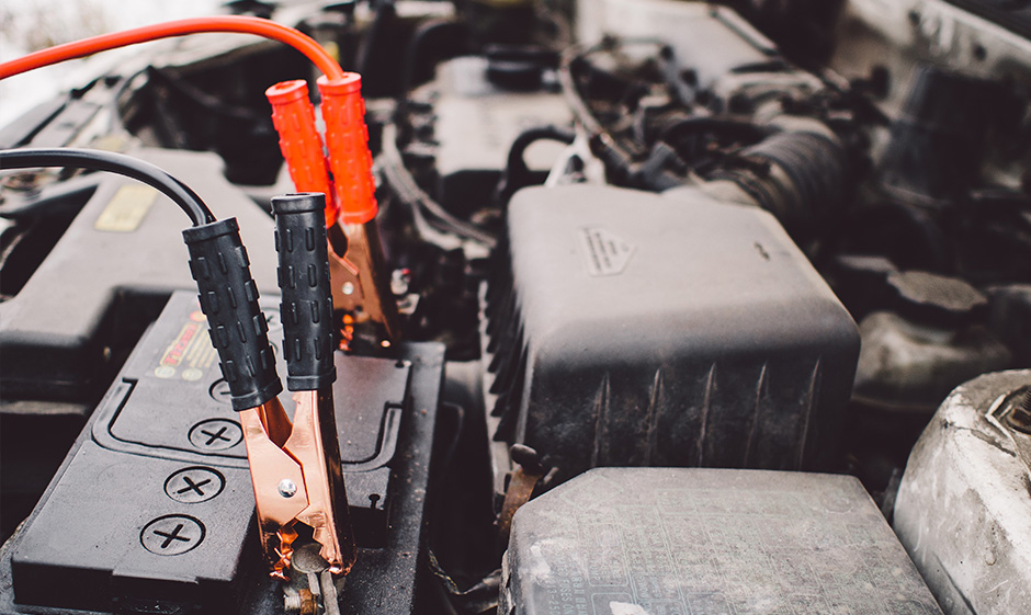 Photo of car battery with black and red cable charging.